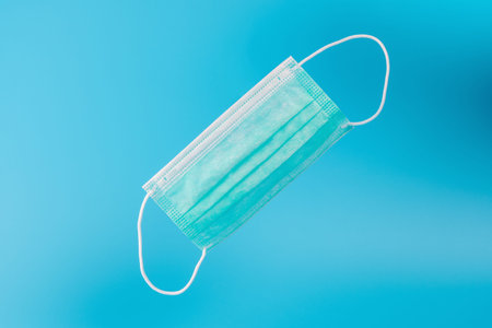 Surgical face mask on blue backdrop. Minimal medical concept.の写真素材