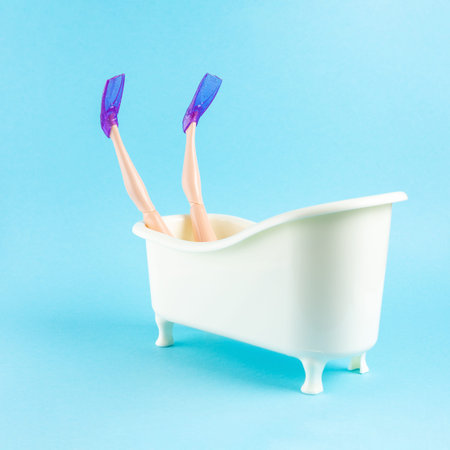 Doll with flippers takes a bath on blue background. Minimal summer vacation concept.