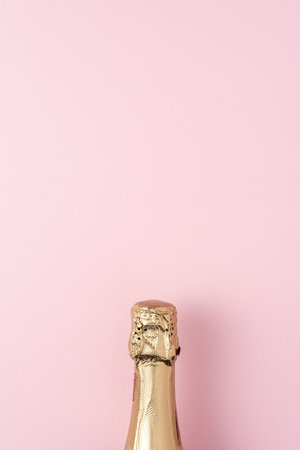 Golden champagne bottle on pink background. Minimal party concept.の写真素材