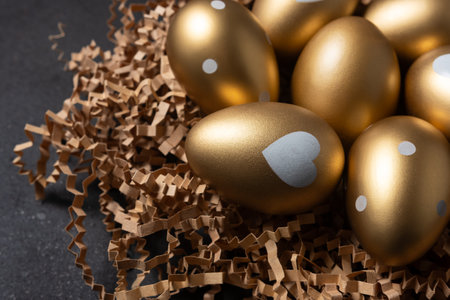 Close-up view of Gold eggs in paper nest on black background.の写真素材