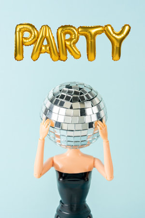Girl in black dress with disco ball head next to helium balloons in the shape of the word PARTY. Minimal holiday concept.の写真素材
