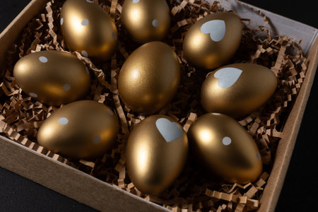 Close-up view of Gold eggs in paper box on black background.の写真素材