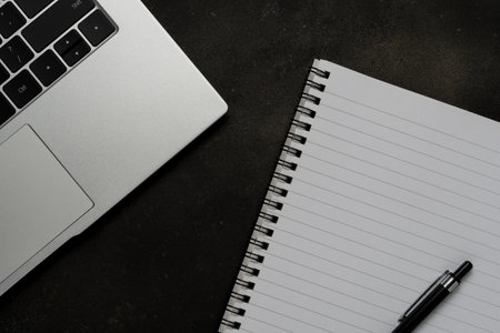 Workspace with blank notebook and laptop on black background. Top view with copy space.の写真素材