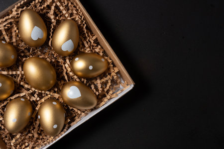 Gold eggs in paper box on black background. Top view.の写真素材