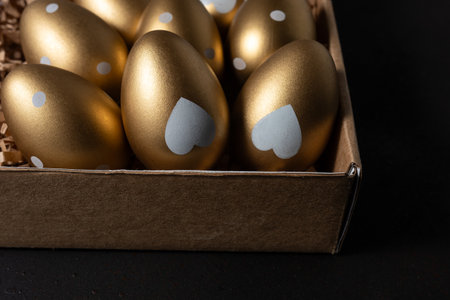 Close-up view of Golden eggs in paper box on a dark table.の写真素材