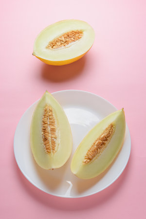 Melon sliced on pastel pink background. Minimal fruit concept.の写真素材