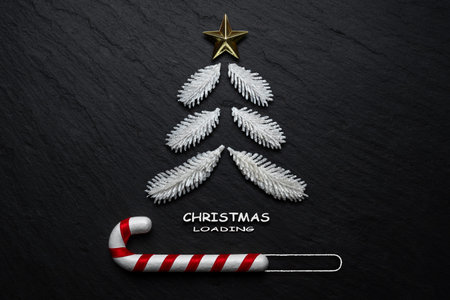 Fir tree and candy cane on black stone background. Minimal Christmas loading concept.