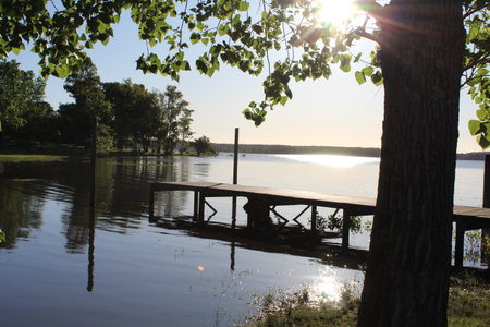 Lake in the early morning with a wooden pier and sunbeamsの写真素材