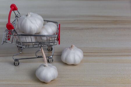 Fresh white garlic in a cart parked on a brown wooden floorの写真素材