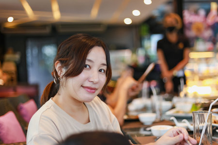 Lifestyle of happy women sitting in a restaurant decorated with soft lights on holidays in relation...