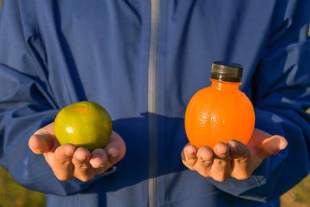 Hand holding fresh oranges and plastic bottles of orange juice Healthy food and drink ideas and copy spaceの写真素材