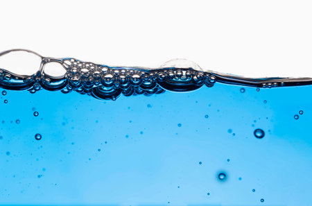 Bubbles on the ground and under the blurred water surface clean blue background.の写真素材