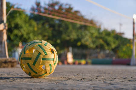 Plastic ball on a cement pitch floor with blurred background and copy space. Sepak Takraw ball close-up Outdoor yellow rattan ball sportsの写真素材