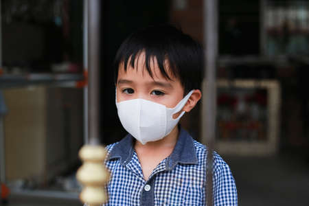 Asian boy wearing a mask and self-quarantine at home to stop the spread of COVID-19 new normal conceptの写真素材