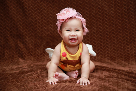 Cute barefoot Asian toddler looking with costume. and wearing a pink bow headband in the indoor...