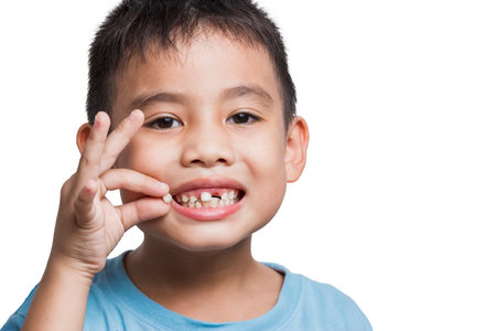 close up boy kid with opened mouth pointing at missing front baby tooth with finger smiling excitedly in on white background First teeth changing Going to dentist to do tooth treatmentの写真素材