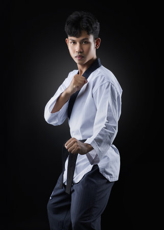 Asian taekwondo athlete standing guard on black background looking to fightの写真素材