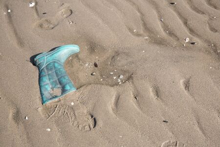 Old green Boot and boot foot print on sandの写真素材