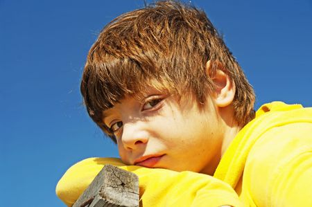 The boy looks in a distance against the dark blue skyの写真素材