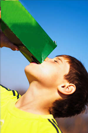 The boy drinking juice from a packageの写真素材