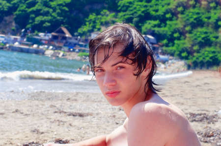 The wet teenager on seacoast sitting sidewaysの写真素材