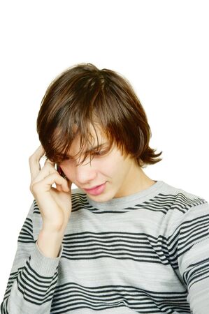 The young man with the long hair calls by a cellular telephone on a white backgroundの写真素材