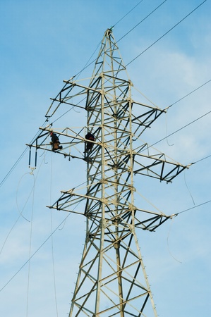 Power linemen at work up on a pylon tower.の写真素材