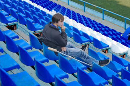 Injury player sits in an empty stadium with a medical crutch