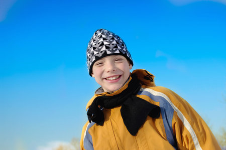 portrait of a teenager in winter clothes on blue sky backgroundの写真素材
