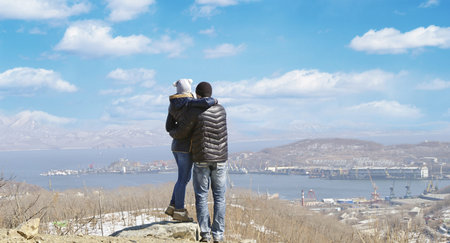 couple in love against the backdrop of the sea port city and clouds look into the distance. winterの写真素材