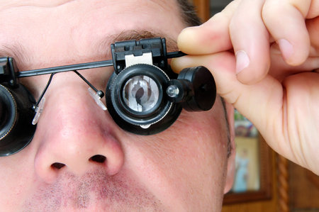 man holding his left hand microscopes special glasses on his face