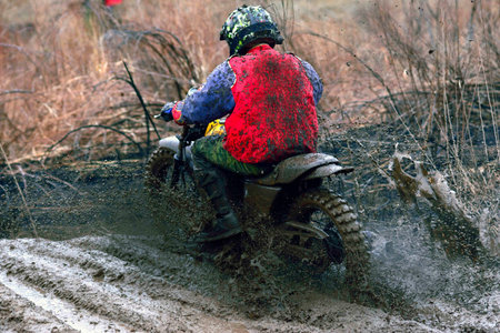 Motocross racer accelerating in dirt track, view from the backの写真素材