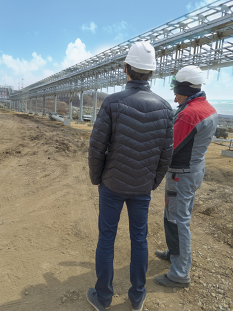 Two engineers discuss the construction of a trestle for pipes in an oil portの写真素材