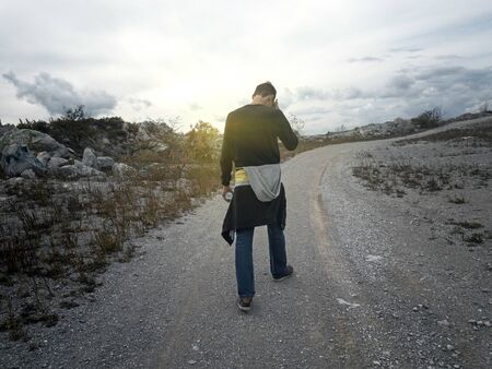 Man goes along the mountain road at sunsetの写真素材