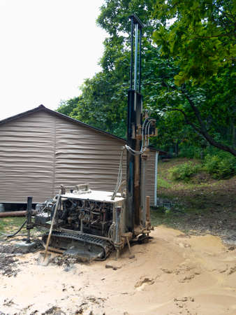 Modern rotary drill rigs bore water well standing near a house under constructionの写真素材