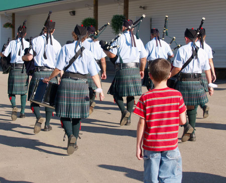 Young boy following a drum and pipes corps