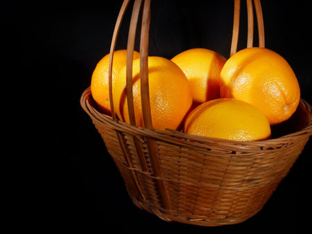 Basket of nice ripe oranges light painted against a black backgroundの写真素材