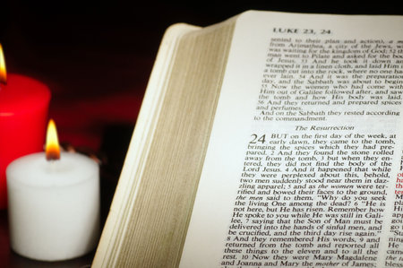 Candles by a Bible open to a passage about the resurrection of Christ
