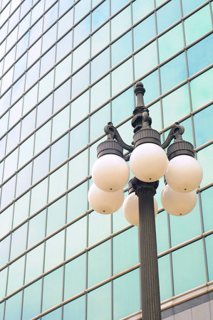 Old-fashioned lamp post in front of modern glass buildingの写真素材