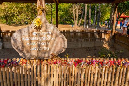PHNOM PENH, CAMBODIA - FEBRUARY 28, 2014: A fenced enclosure and sign marks a mass grave at the Choeung Ek Genocidal Center, commonly known as the Killing Fields. The center memorializes the thousands of victims who died here.のeditorial素材