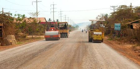 BATTAMBANG PROVINCE, CAMBODIA - FEBRUARY 19 2014: A road construction crew smooths down new gravel on a stretch of the main highway between Seam Reap (location of Angkor Wat) and Battambang.のeditorial素材