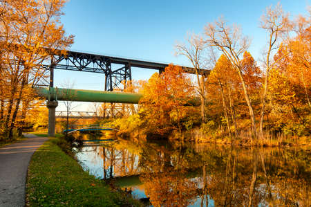 The Ohio Canal flows placidly under a railroad trestle and sewage pipe near Cleveland on a late autumn afternoonの写真素材