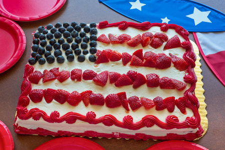 A patriotic themed sheet cake decorated with strawberries and blueberries to represent the US flag,...