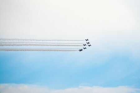 Air show, aircraft group flying leaving smoke trail with a cloudy blue sky in the backgroundの写真素材