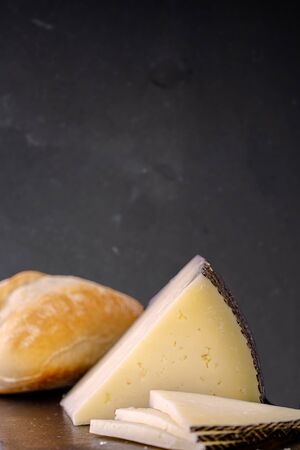 Manchego cheese and bread on a table with a stone wall in the backgroundの写真素材