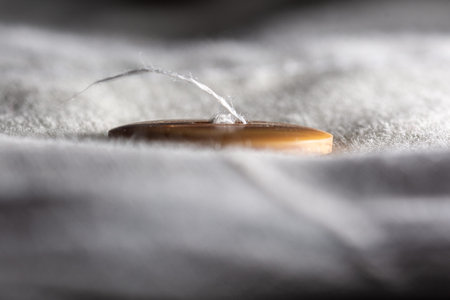 Loose thread in the seam of a button on a bedspread