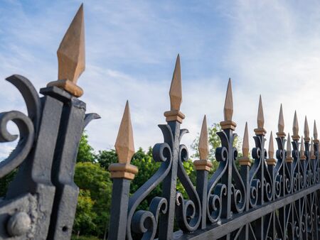 Details of an old metal fence, entrance to the Buen Retiro park, with golden spearheads on topの写真素材