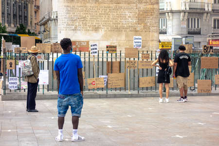 Madrid, Spain; 07/06/2020: Black boy looking at the banners left on a fence after the demonstration of the black lives matter in Madridのeditorial素材
