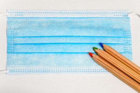 Back to school during the Covid-19 pandemic, photograph of some pencils and a mask to represent the...