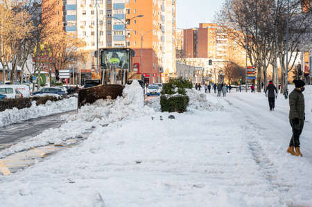 Fuenlabrada, Madrid, Spain; 10-01-2021: Excavator removing the large amount of snow from the road after the storm "Filomena"のeditorial素材